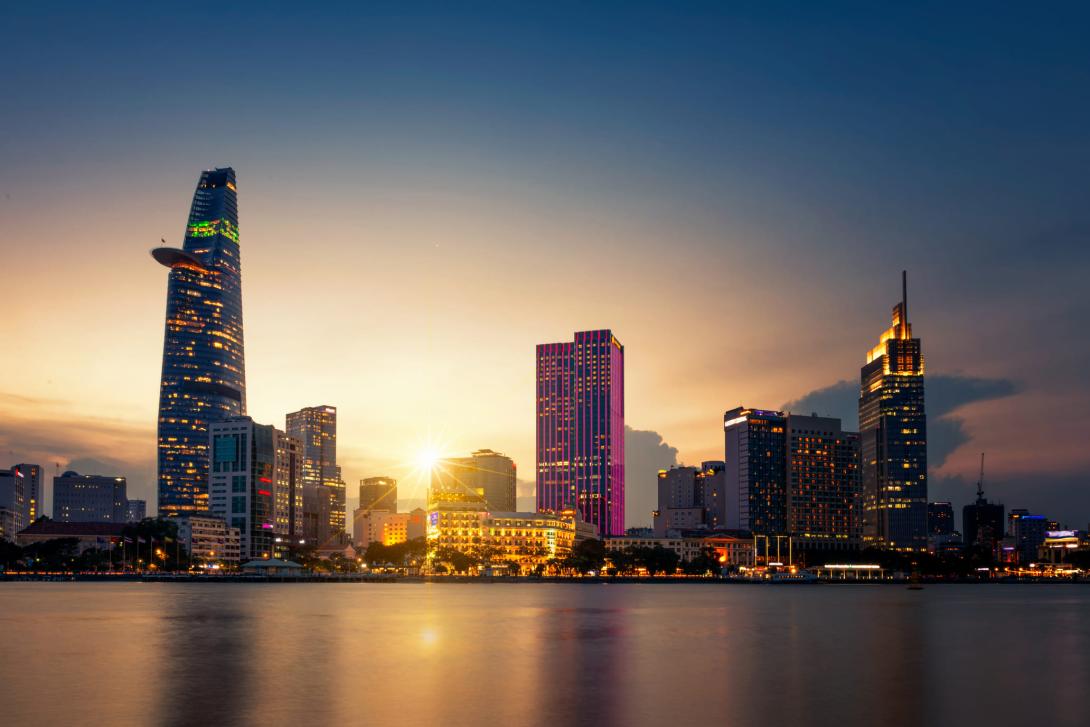 A stunning sunset of the Hoi Chi Minh skyline The sun setting on a brightly lit Hoi Chi Minh, casting long shadows onto the water